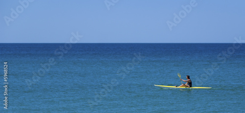 athletic young man paddles kayak beautiful blue day calm ocean