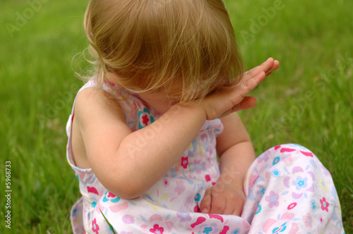 A preschool girl in a dress looking sad.