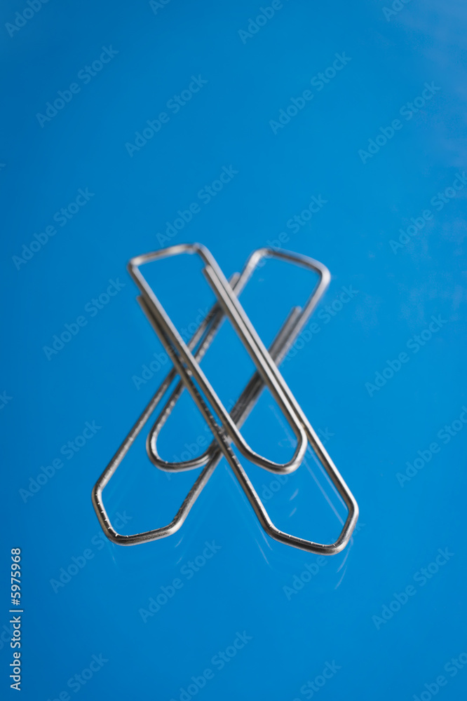 Paper clip over a blue reflective background