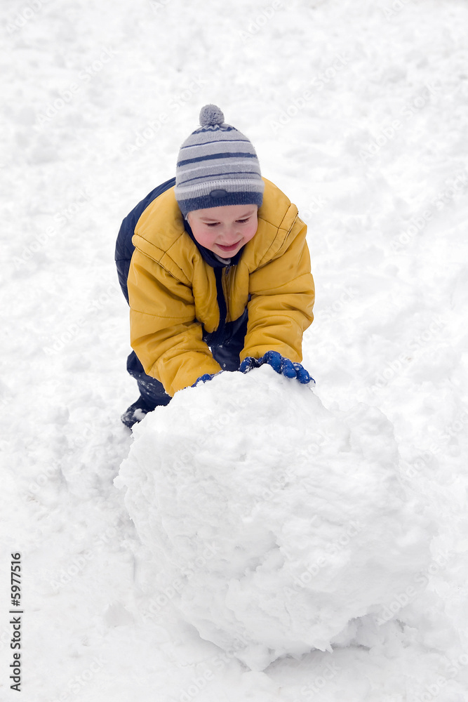 The boy rolls snow whom in winter day