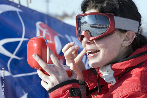 sport girl snowboarder applying face pack outdoors in mountain