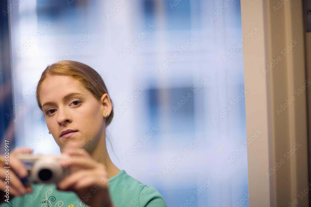 Serious young woman taking pictures with digital camera. Serious young woman taking pictures with digital camera.
