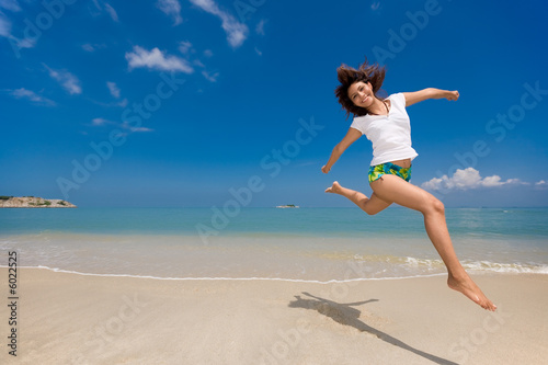 young beautiful girl jumping happily at the beach