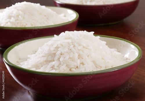 Several bowls of organic white rice on wooden counter.