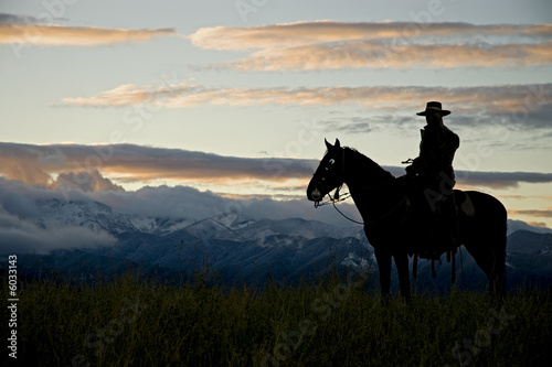 Cowboy silhouette against dawn sky