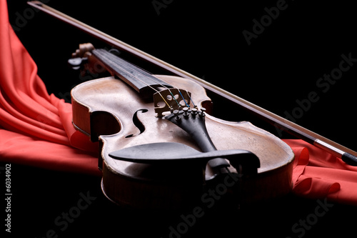 old violin with fiddlestick on folded scarlet silk photo