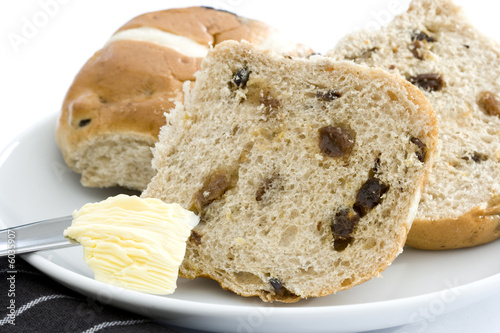 Cut hot cross buns with butter on knife photo