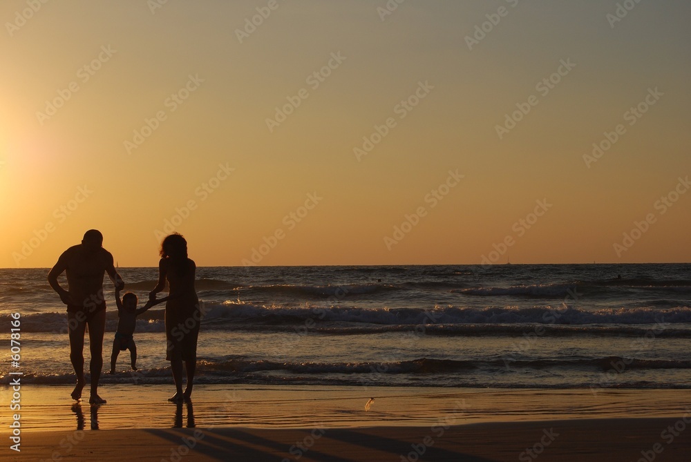 happy family on the sea beach at the moment of sunset