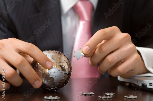  businessman playing a globe puzzle