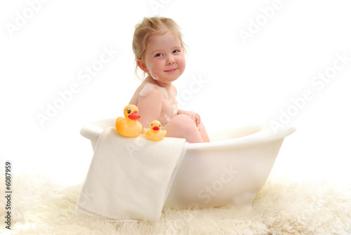 A young girl with bubbles in bathtub.