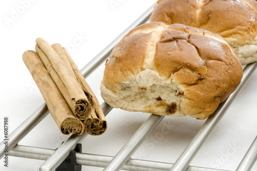 Hot cross bun on cooling rack with cinnamon sticks photo