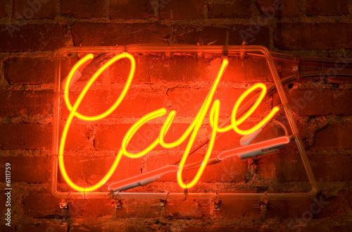 a neon sign on a brick wall outside of a cafe