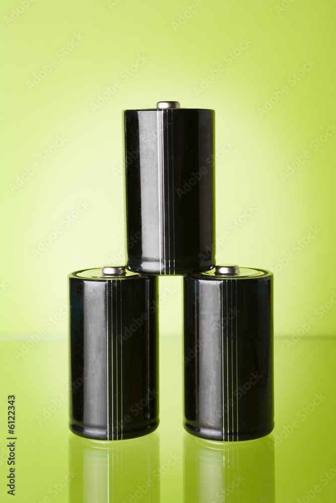 Obraz premium Three batteries on green background