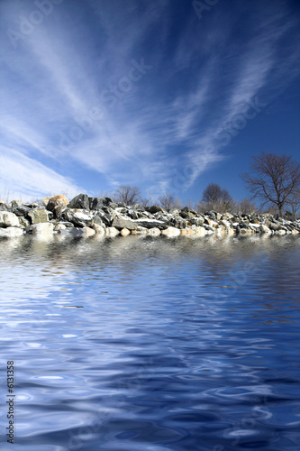 Frozen shoreline with iced rocks and blue sky