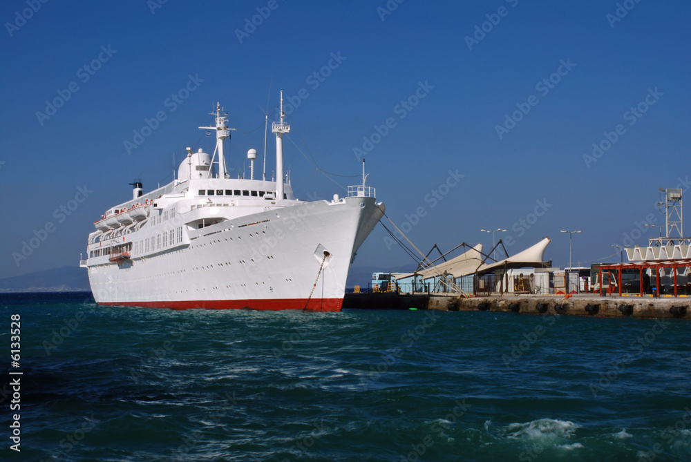 Huge white cruise ship  is docking in the greek harbour