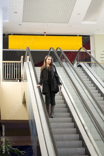 brunette in black coat going down stair in commercial center