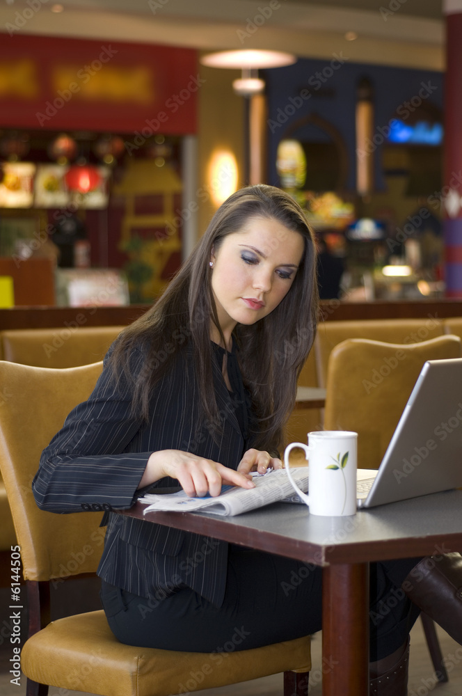 pretty woman sitting in a cafe with watching at news paper