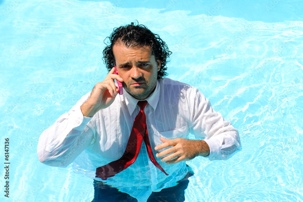 Wet Businessman talking on phone in the Swimming Pool .