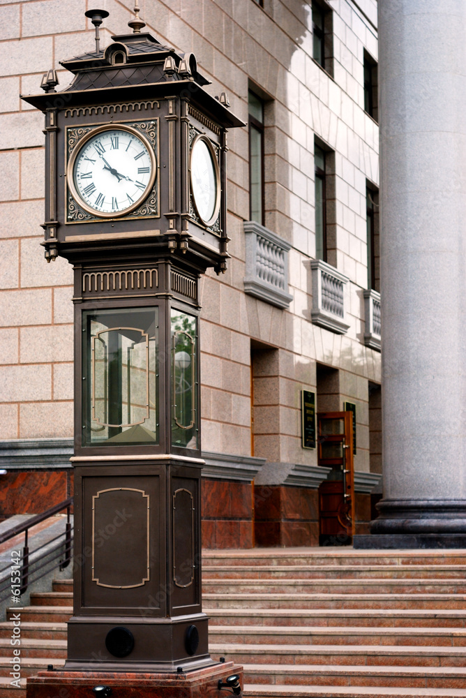 Town oldfashioned clock near building entrance with columns Stock