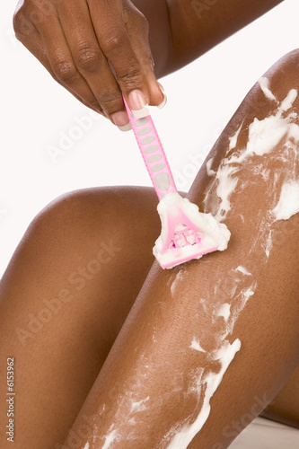 Close up of African-American woman shaving her legs with razor