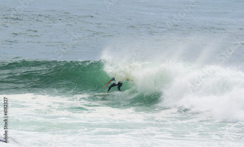 a surfer surfing out of a big wave about to dump him