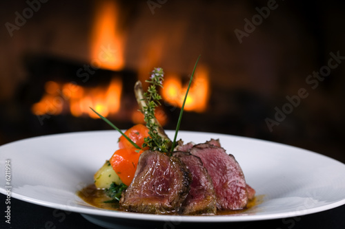 Lamb chops with vegetables in front of a fireplace