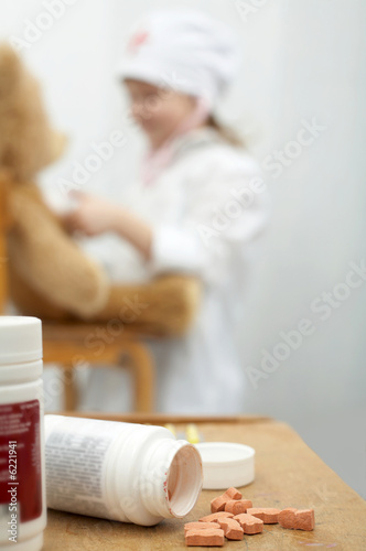 Pills close-up with a girl playing doctor foreground