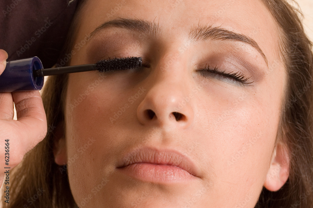 Applying eyebrush mascara on beauty woman's face
