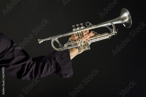 Somebody holding trumpet on dark background.