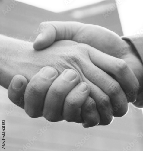 close up handshake with blue office building in background