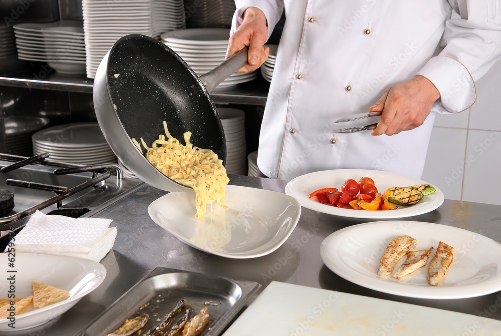 Obraz premium Chef preparing pasta on professional kitchen in restaurant