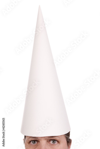 Woman in a dunce cap with eyes open over a white background