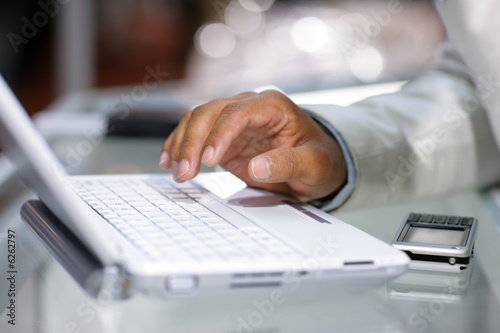 Close-up of male hand typing on white laptop computer photo