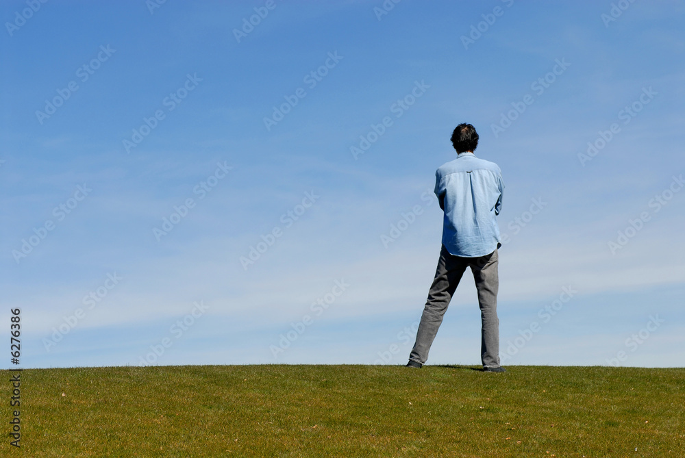 Man standing on hill with arms crossed Man standing on hill with arms crossed