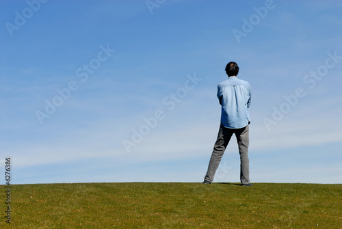 Man standing on hill with arms crossed
