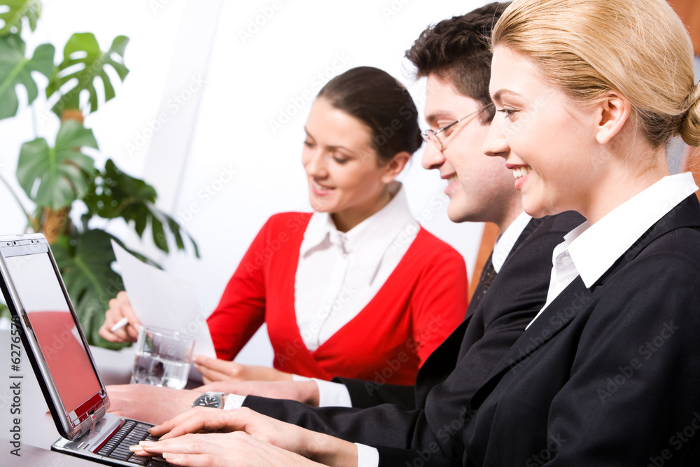 Row of three business people sitting at the table and working Row of three business people sitting at the table and working