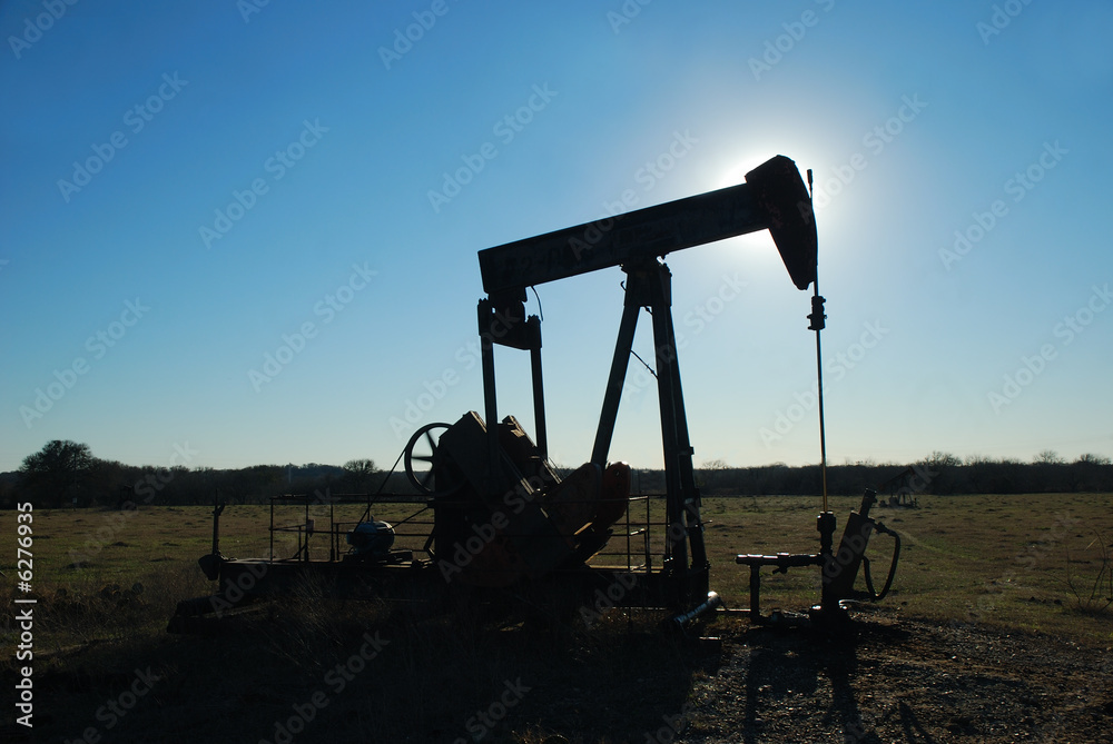 Silhouette pump jack backlight by the afternoon sun. Silhouette pump jack backlight by the afternoon sun.