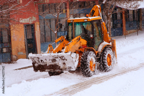 a truck ceaning the street while snowing