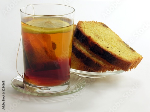 glass of tea with lemon slice and pieces of biscuit cake