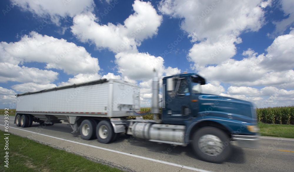 Blurred semi-truck seen under crazy clouds. Blurred semi-truck seen under crazy clouds.