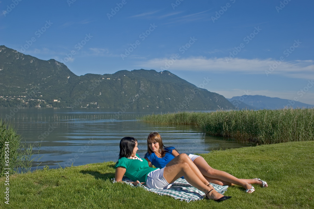 woman lengthened in the grass at the edge of a lake