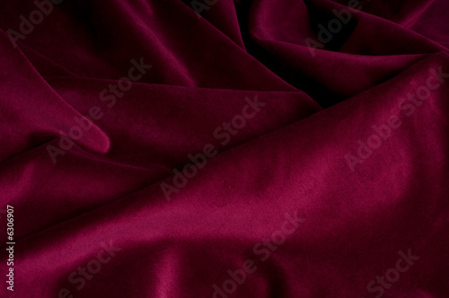 Dark carmine fabric background with many folds