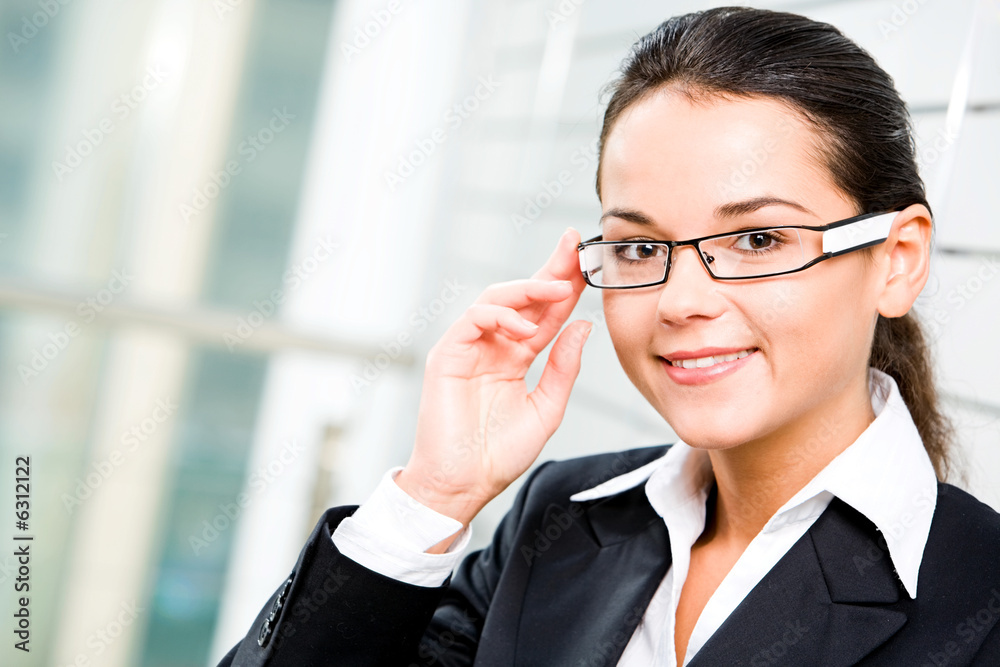 Self-confident woman in suit touching her glasses Self-confident woman in suit touching her glasses