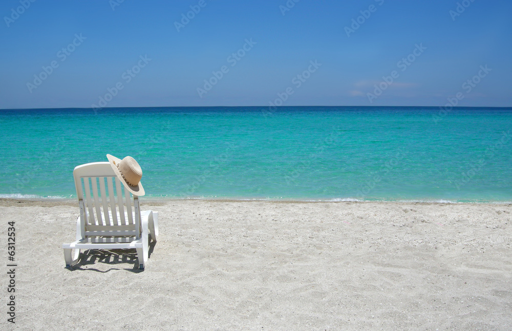 Empty tropical beach chairs on sand at shoreline Empty tropical beach chairs on sand at shoreline