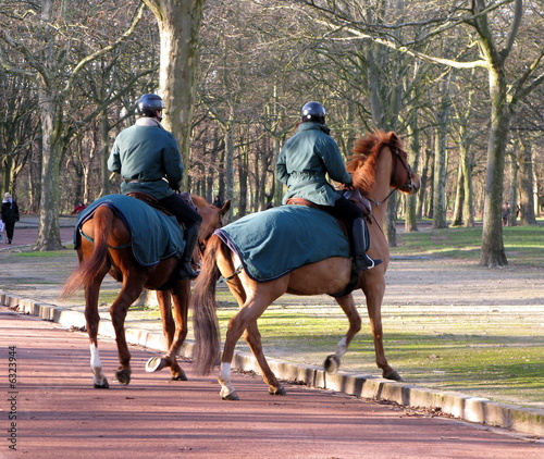 Gardes à cheval dans une allée de parc parisien.