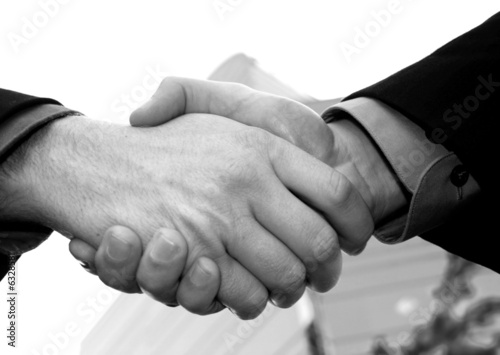 close up handshake with blue office building in background