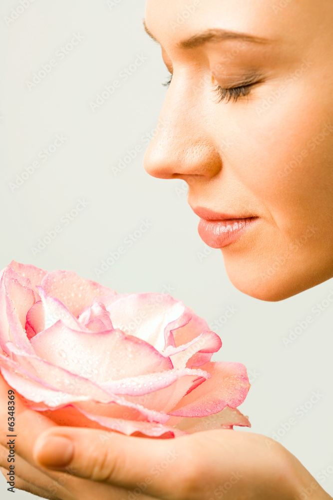 Fototapeta premium Young pretty woman enjoys a smell of a pink rose