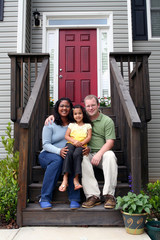 A family sitting in front of their home