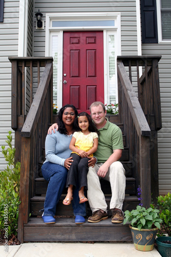 A family sitting in front of their home