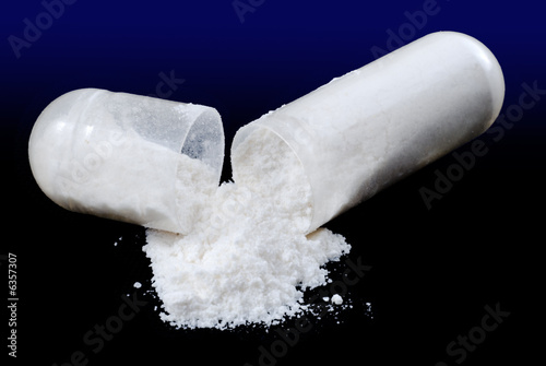 Pill capsule broken open with powder spilling out